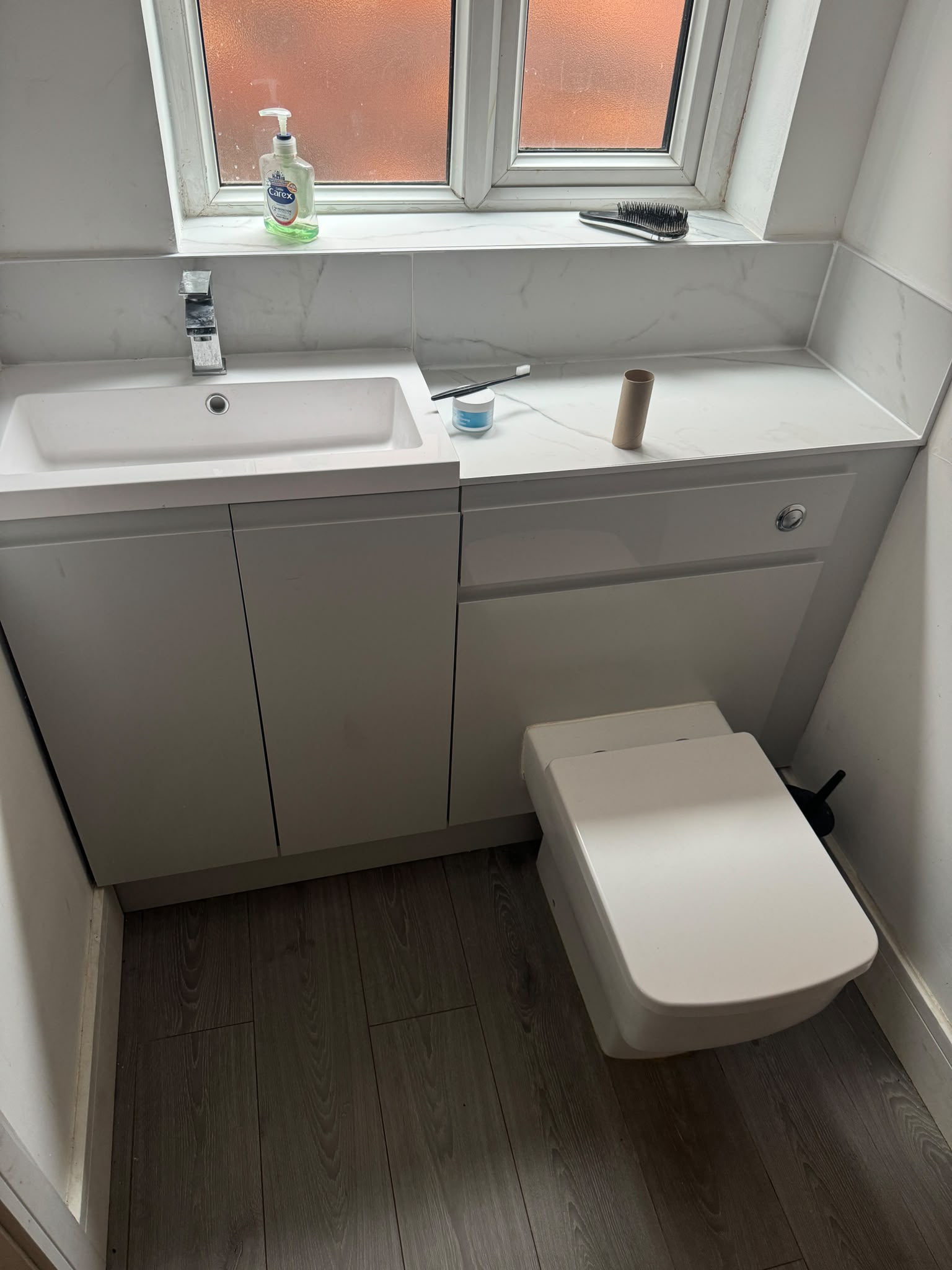Compact bathroom refit with marble-effect surround and combined vanity unit